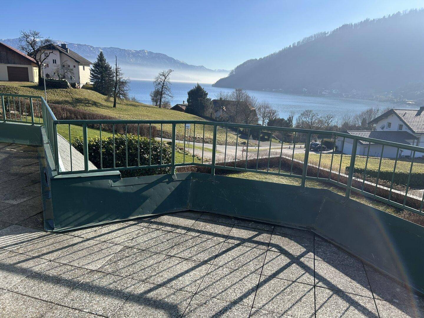 Geräumige Terrasse mit Fliesenboden und atemberaubendem Blick auf den See und die umliegenden Berge.