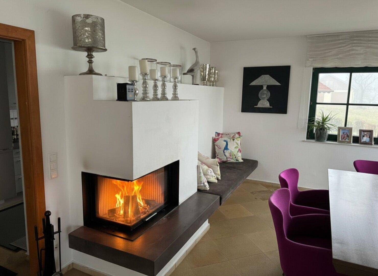 Moderner Kamin als Raumteiler zwischen Wohn- und Essbereich, mit gemütlicher Sitzbank.