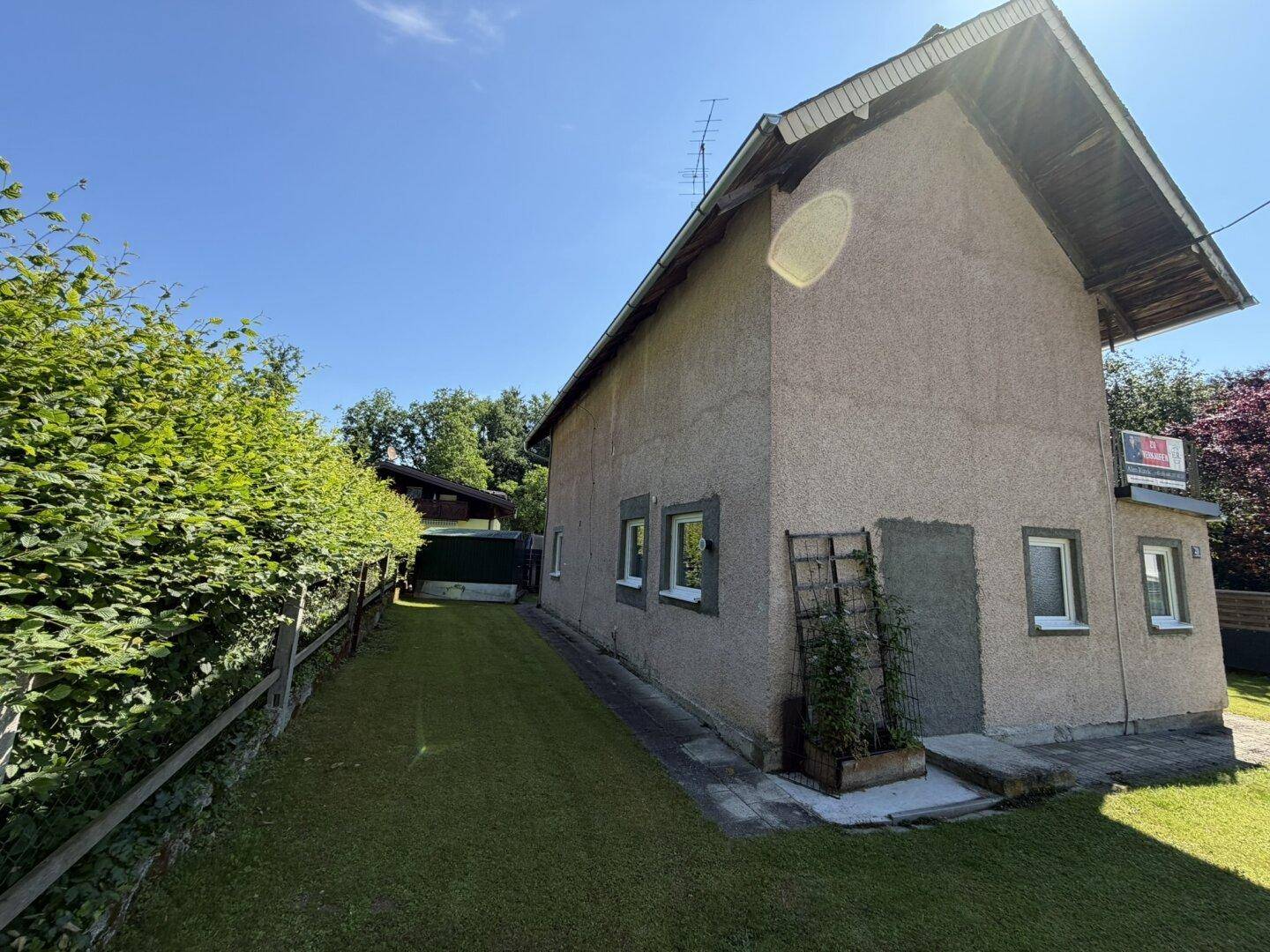 Seitenansicht des Hauses mit schmalem Rasenstreifen und einer gepflegten Hecke.