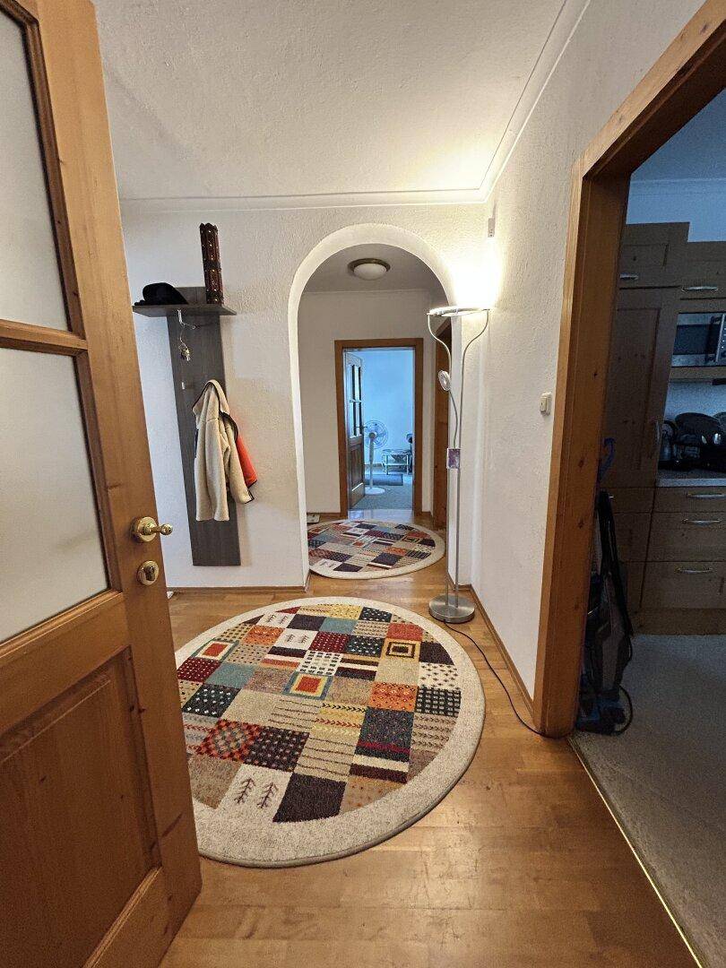 Heller Flur mit Holzboden, bunten Teppichen und einer praktischen Garderobe.