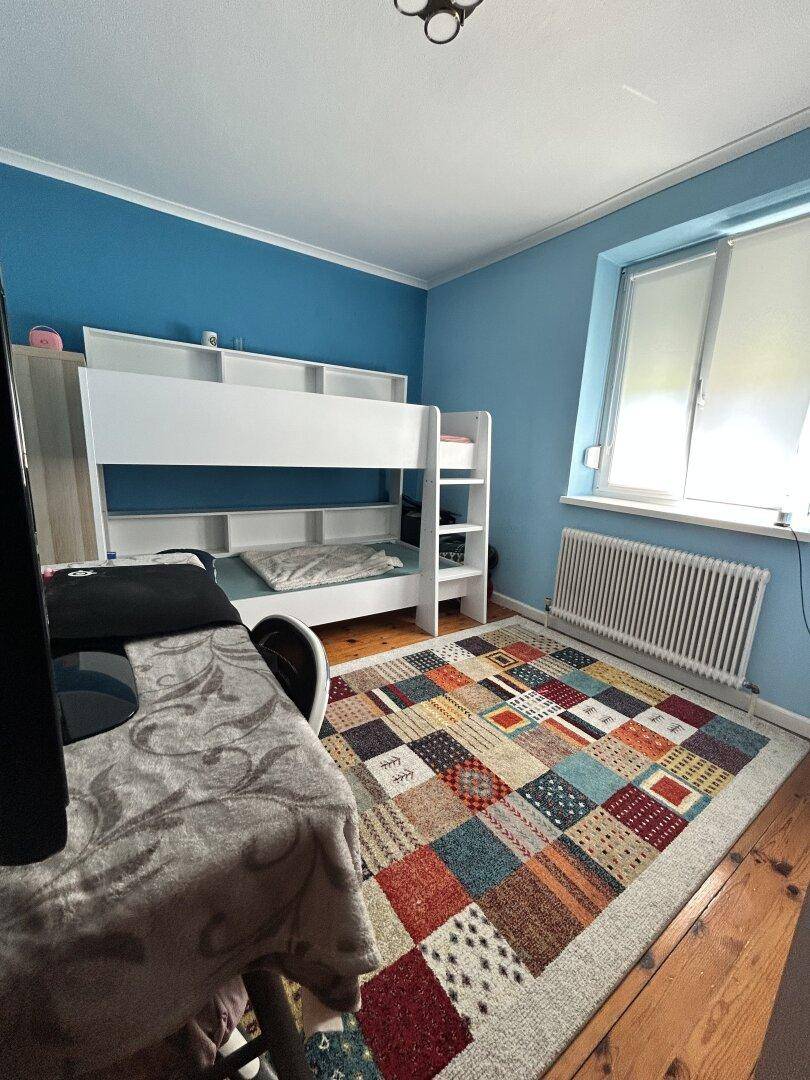 Kinderzimmer mit Etagenbett, blau gestrichenen Wänden und Holzboden.