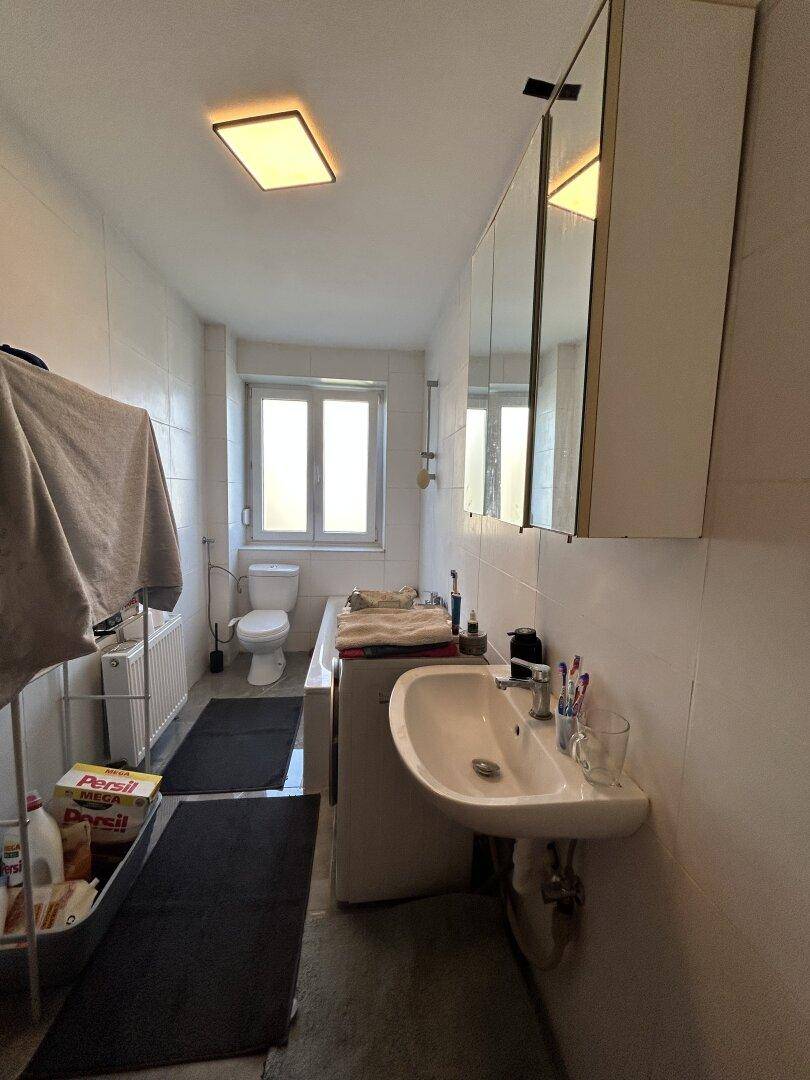 Funktionales Badezimmer mit Badewanne, Waschbecken, WC und einem Fenster für Tageslicht.