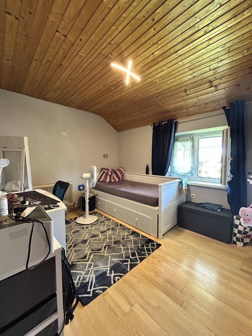 Schlafzimmer mit Holzboden, Holzdecke und einem Einzelbett mit Stauraum.