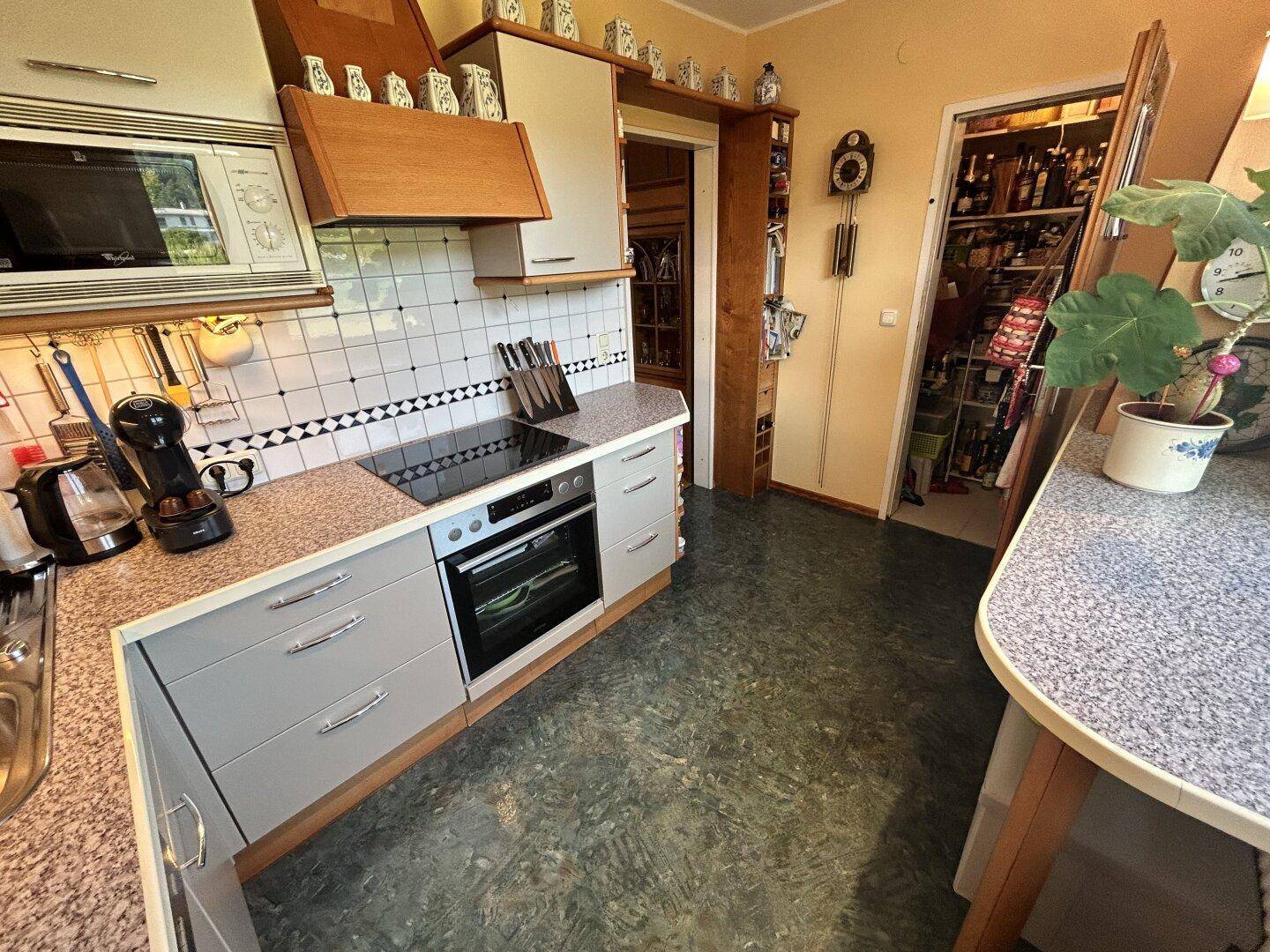 Funktionale Küche mit Kochfeld, Backofen und Zugang zu einem praktischen Vorratsraum.