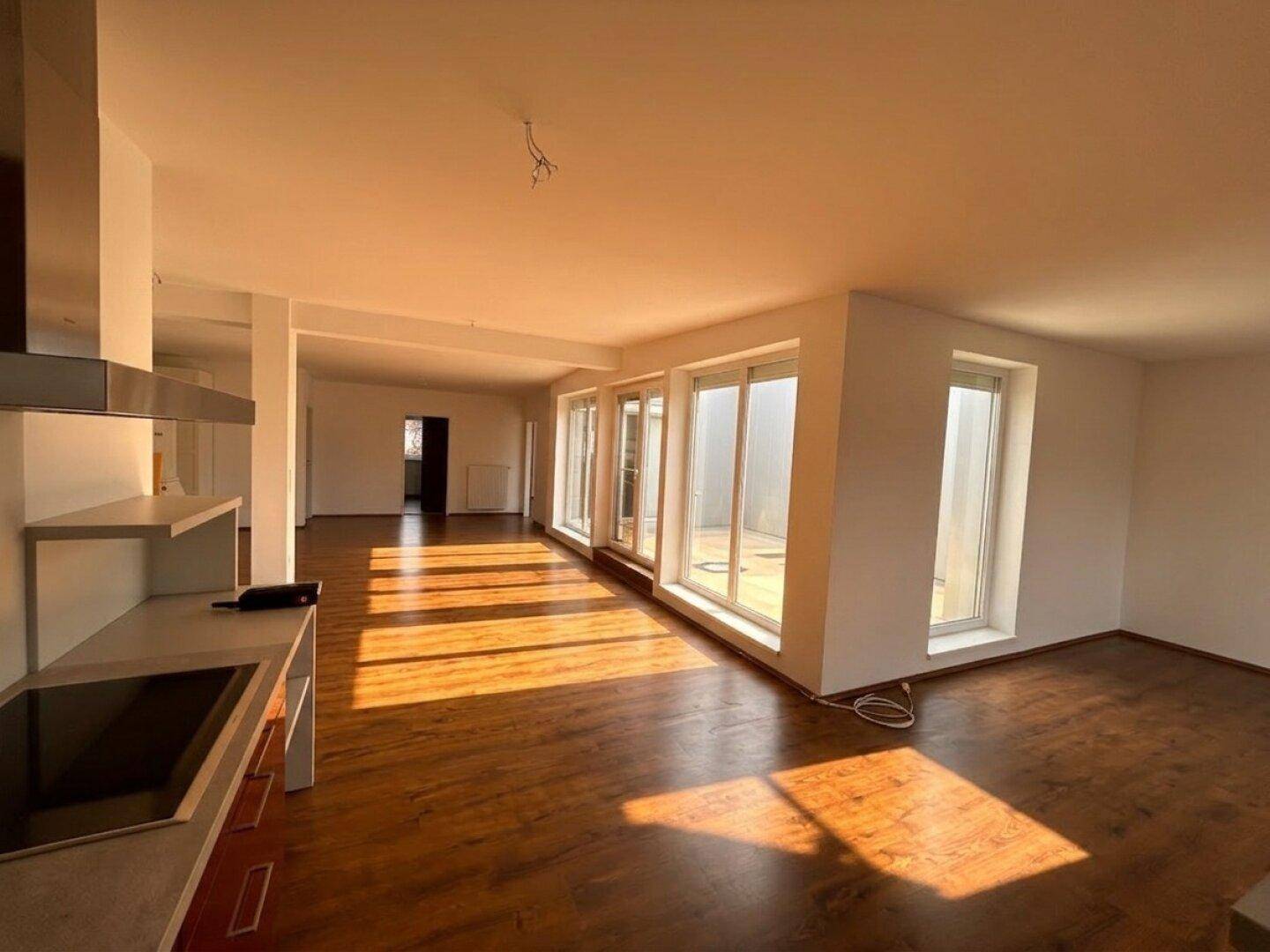 Helle, offene Küche mit Kochfeld und weitem Blick in den Wohnbereich mit Terrassenzugang.