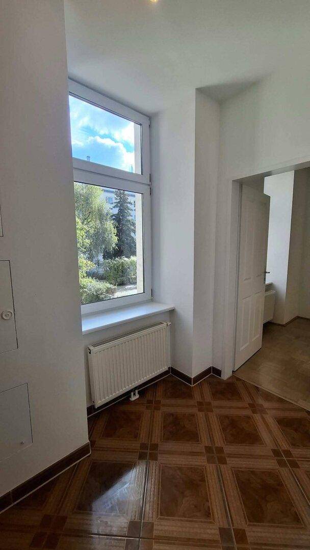 Heller Flurbereich mit gemustertem Fliesenboden und einem Fenster mit Blick ins Grüne.