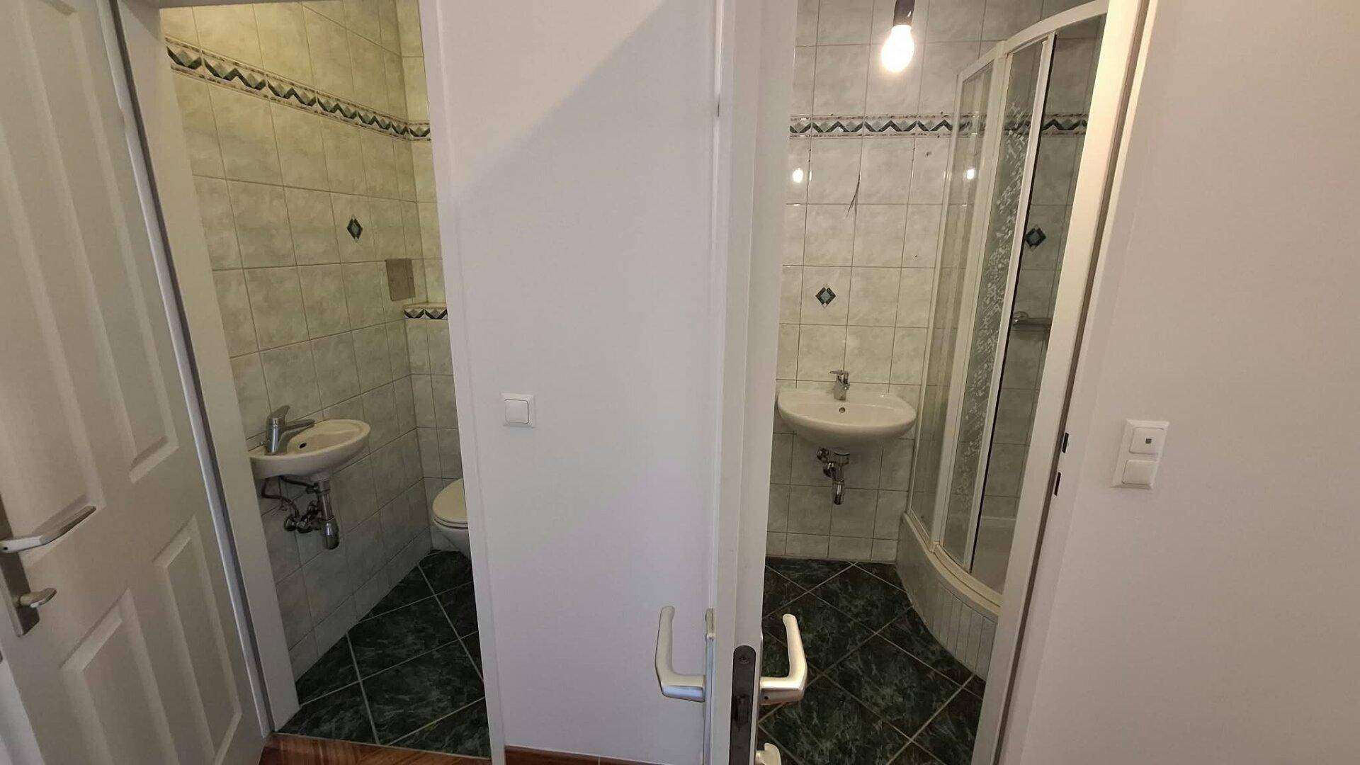 Blick in zwei separate Räume: eine Toilette und ein Badezimmer mit Duschkabine.