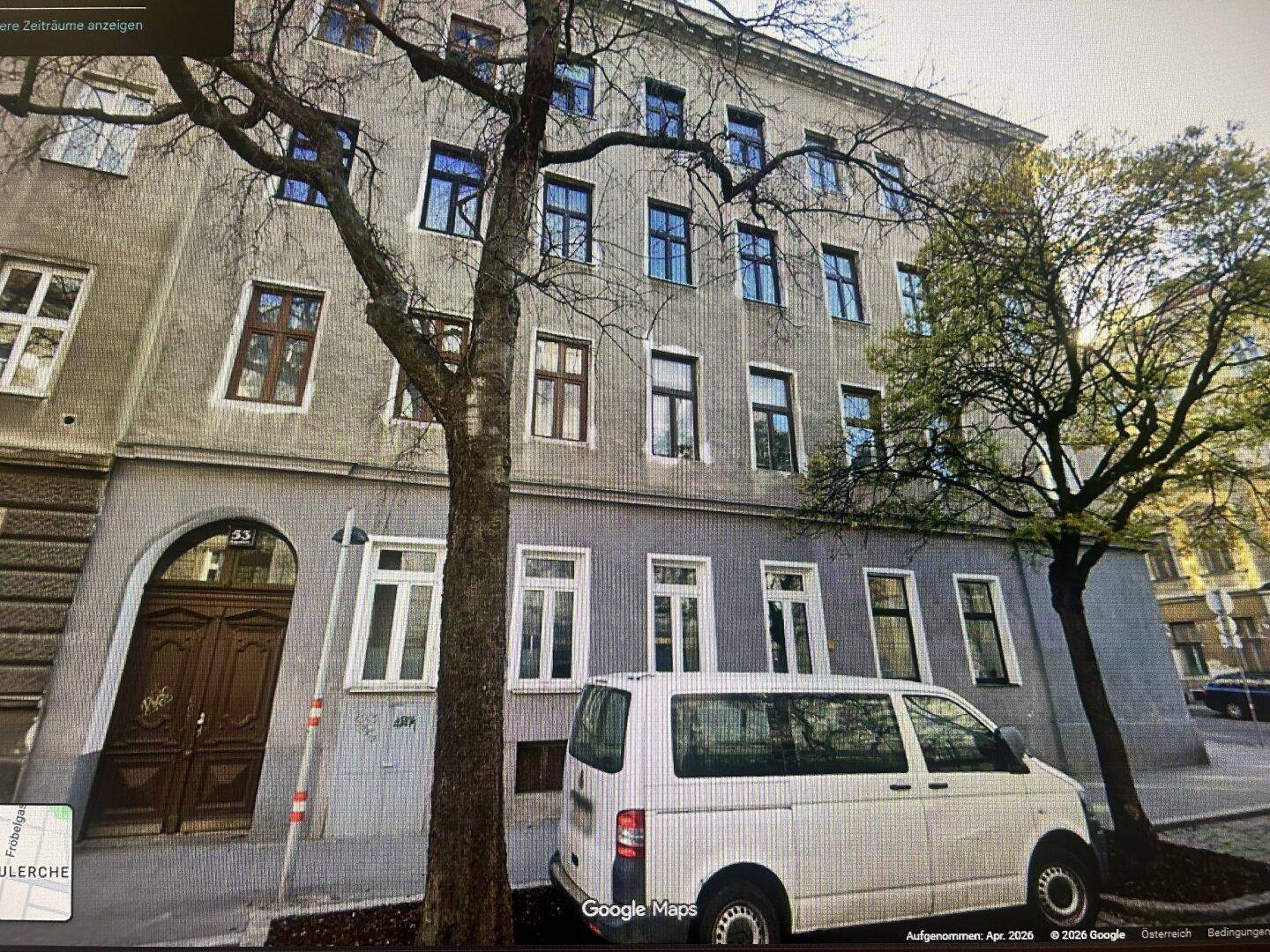 Ansicht eines Mehrfamilienhauses von der Straße mit parkendem Lieferwagen.