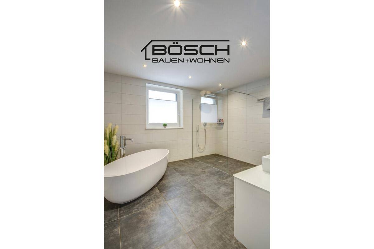 Modernes Badezimmer mit freistehender Badewanne, begehbarer Dusche und Fenster, ausgestattet mit grauen Fliesen.