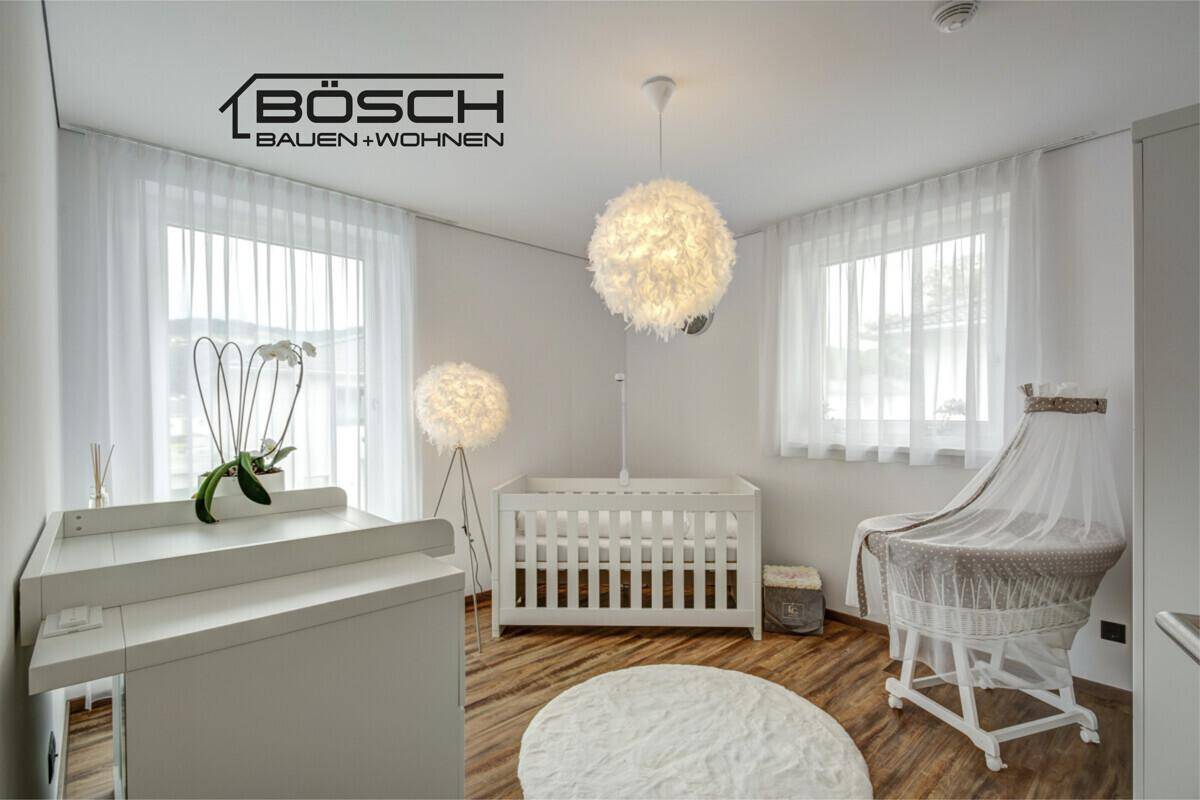 Helles Kinderzimmer mit Babybett, Wickeltisch und großen Fenstern für viel Tageslicht.