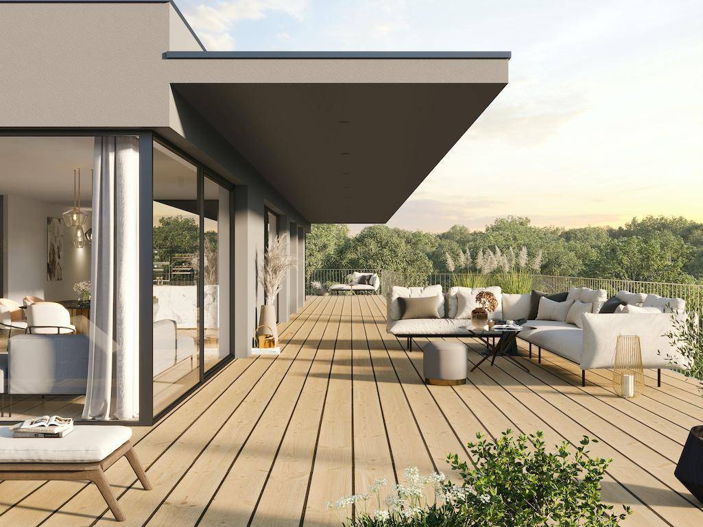Weitläufige Holzterrasse mit bequemen Loungemöbeln und weitem Blick ins Grüne.