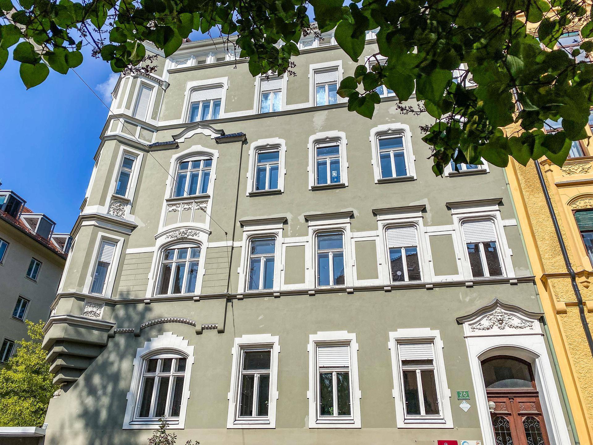 Detailansicht der Fassade eines Altbaus mit vielen Fenstern, einem dekorativen Erker und Rollläden.