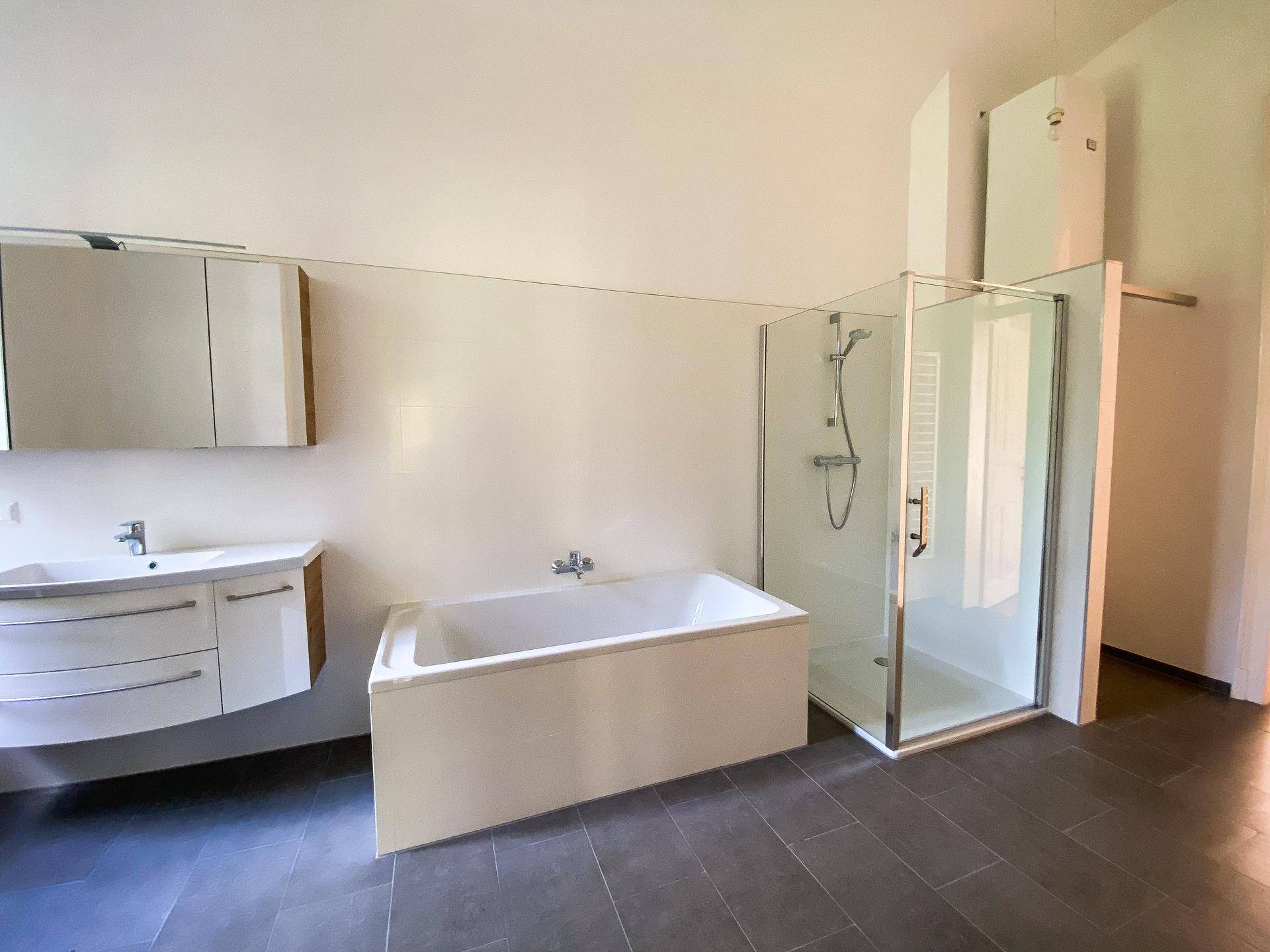 Modernes Badezimmer mit Badewanne, Duschkabine und einem Waschtisch mit Spiegelschrank.