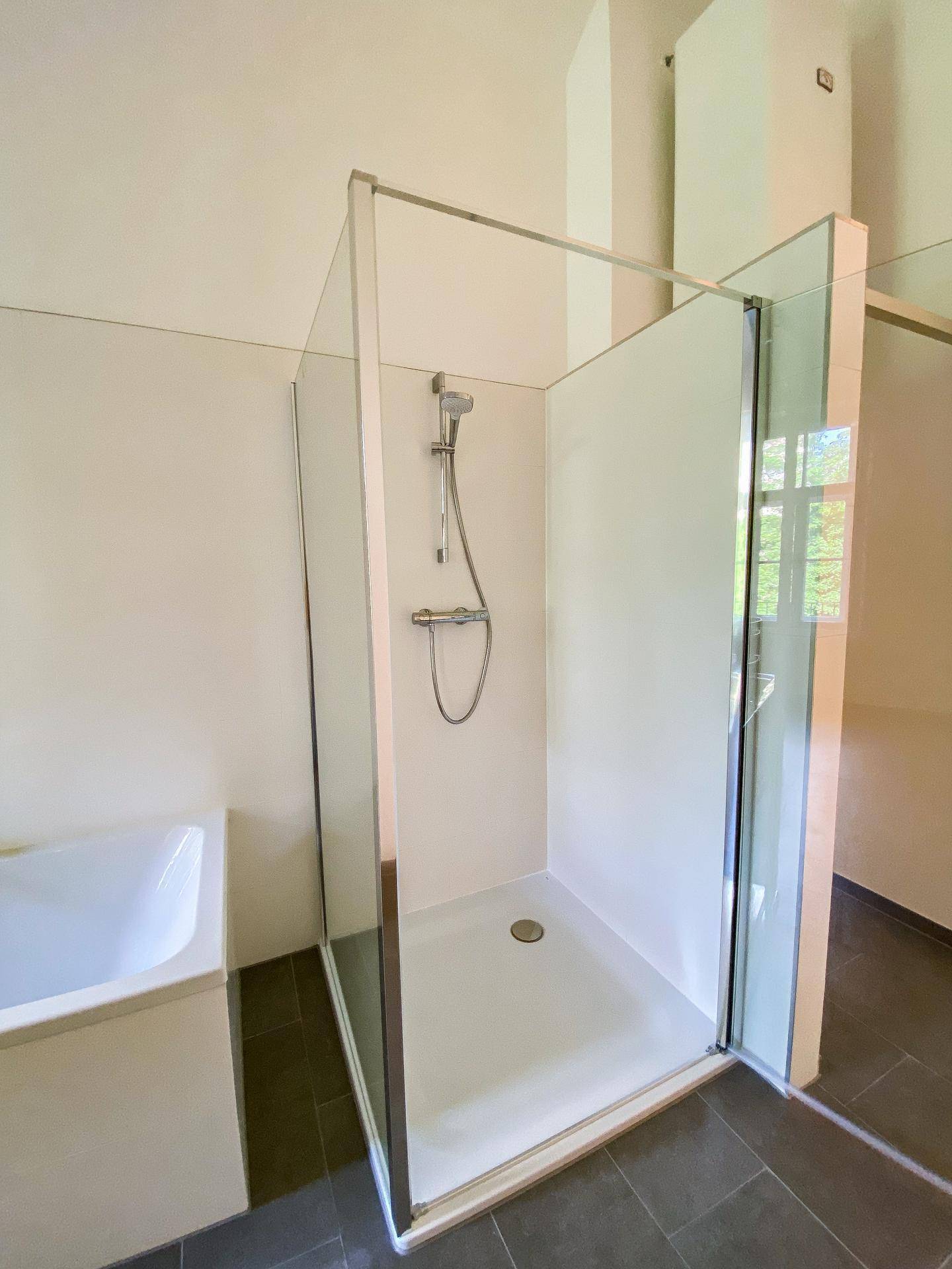Moderne Duschkabine mit Glaswänden und einer Regendusche in einem hellen Badezimmer.