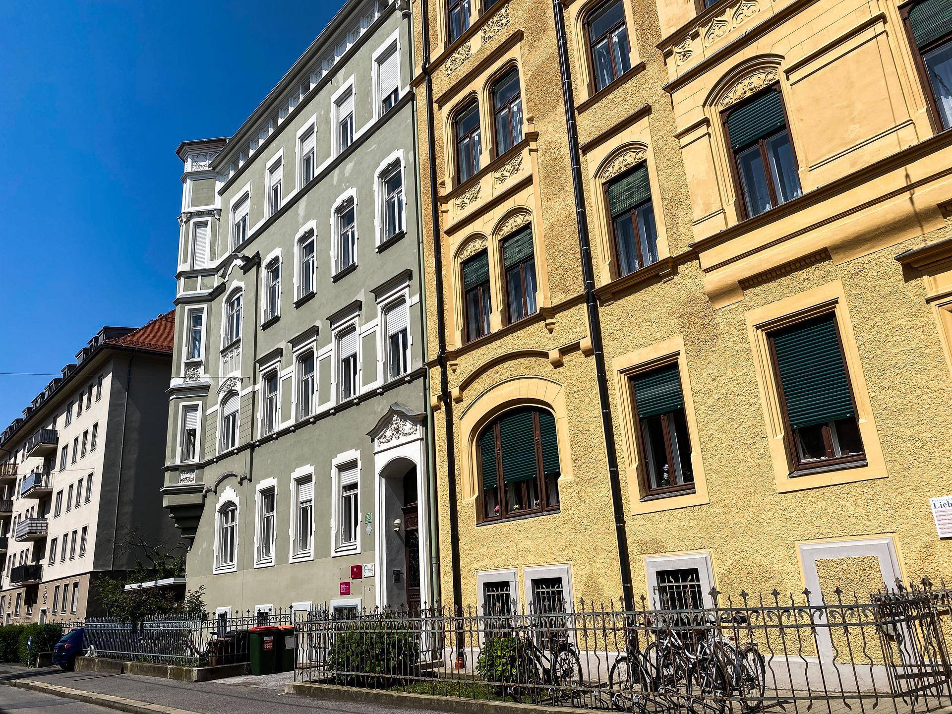 Straßenszene mit mehreren historischen Gebäuden, die unterschiedliche Fassadenfarben und architektonische Details aufweisen.