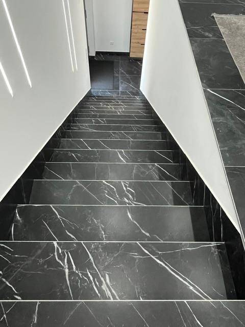 Elegante Treppe mit schwarzem Marmor und weißen Akzenten, die die Etagen verbindet.