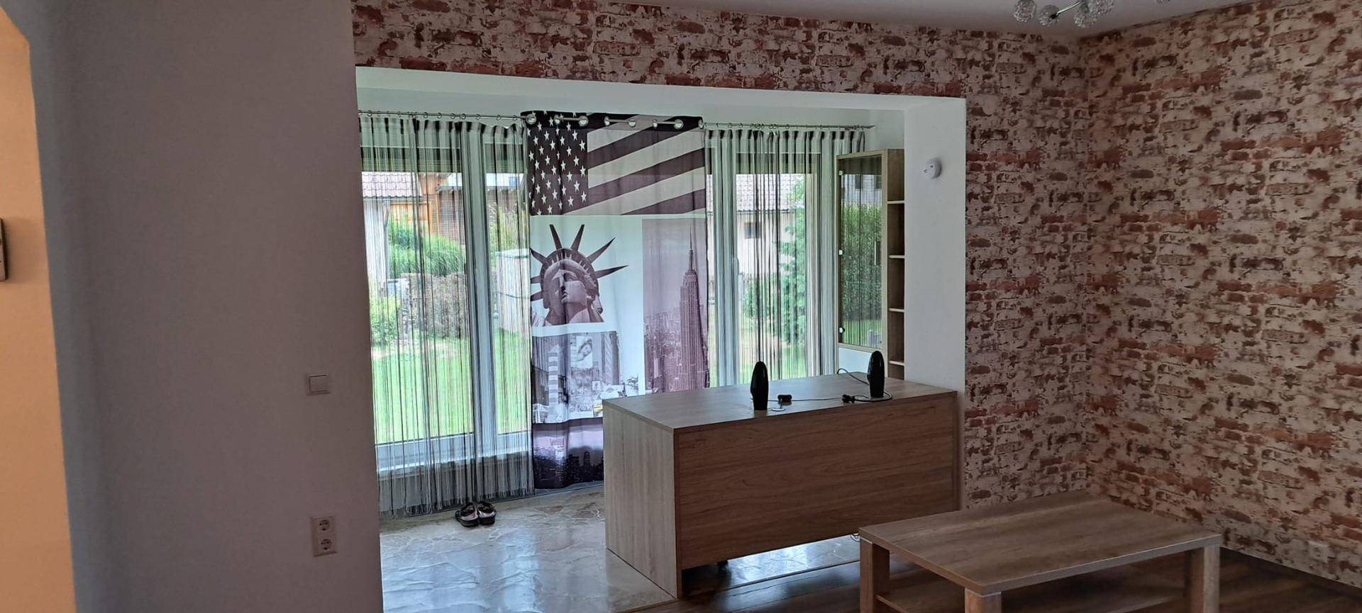 Wohnzimmer mit Ziegelstein-Tapete und großem Fenster mit Blick in den Garten.