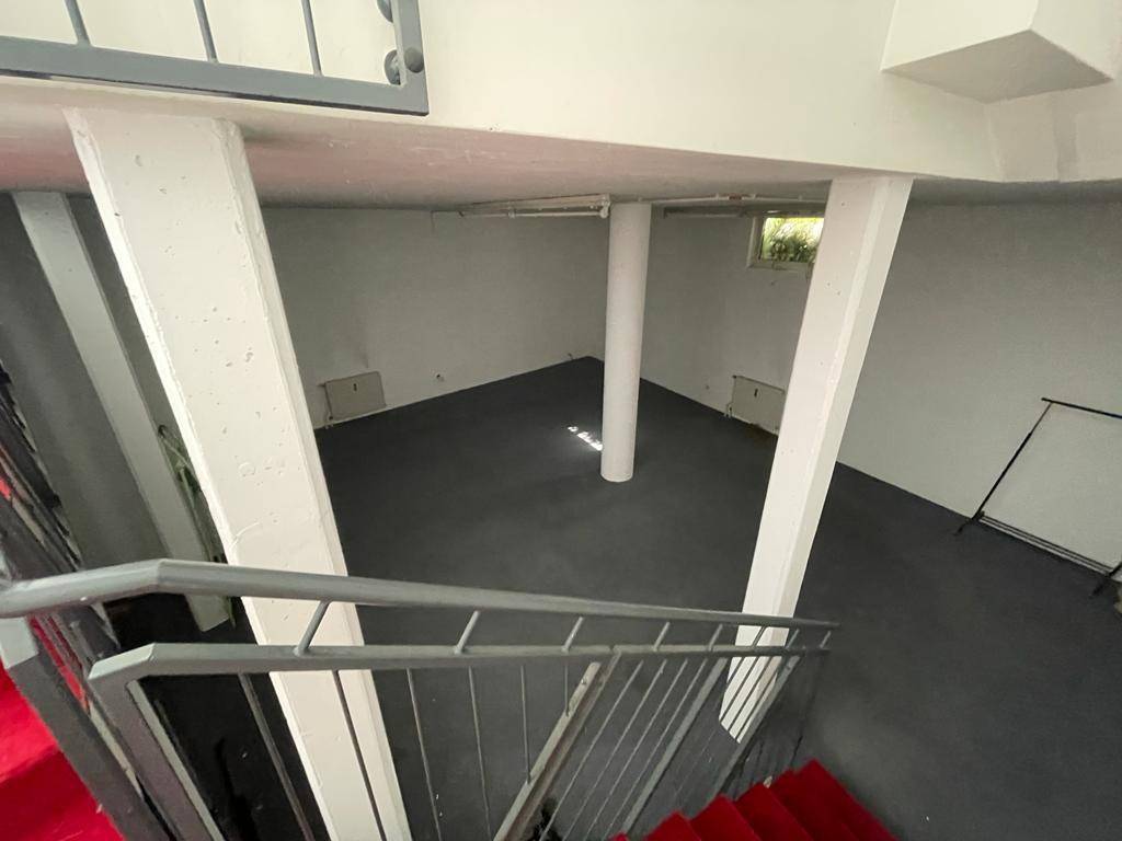 Untergeschoss mit dunklem Bodenbelag, tragenden Säulen und einem kleinen Fenster für Tageslicht.