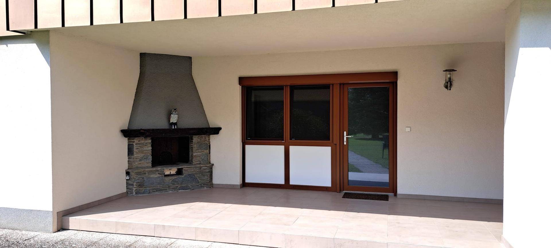 Überdachte Terrasse mit Außenkamin und Zugang zum Garten, ideal für gesellige Abende.