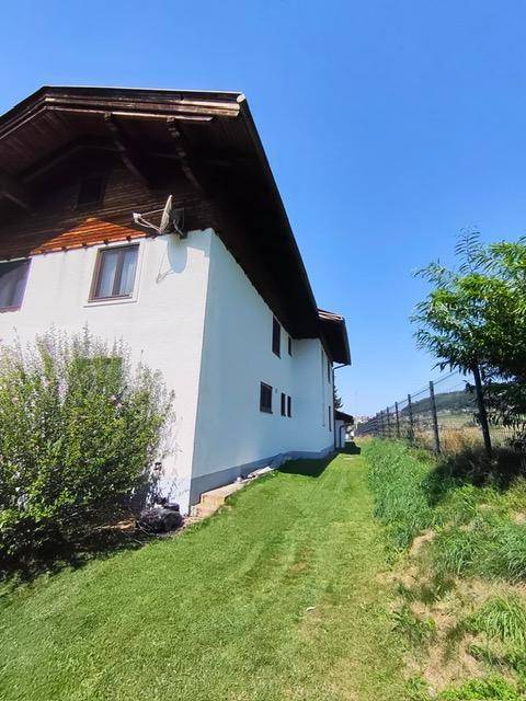 Seitenansicht des Hauses mit einem gepflegten Rasenweg und Blick auf die umgebende Natur.