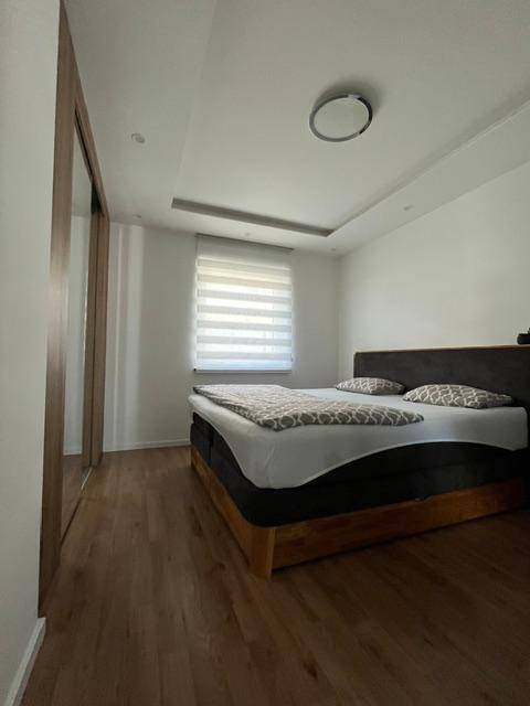 Helles Schlafzimmer mit Holzboden, Doppelbett und großem Spiegelschrank.
