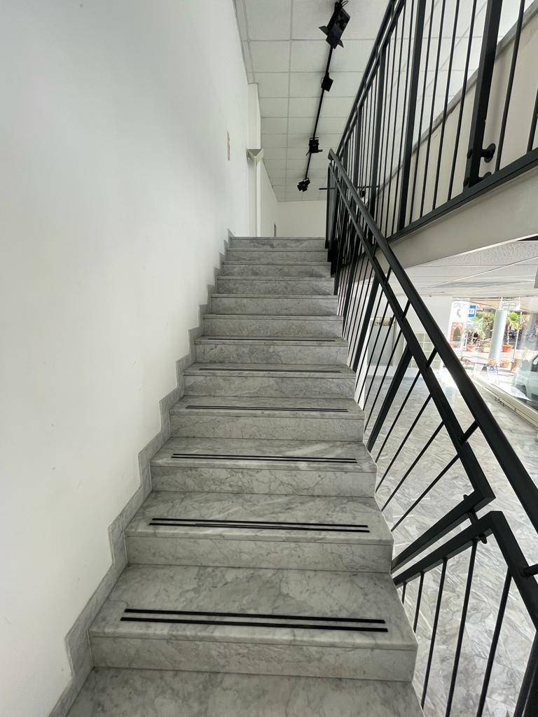 Elegante Marmortreppe mit schwarzem Metallgeländer und rutschfesten Streifen, die nach oben führt.