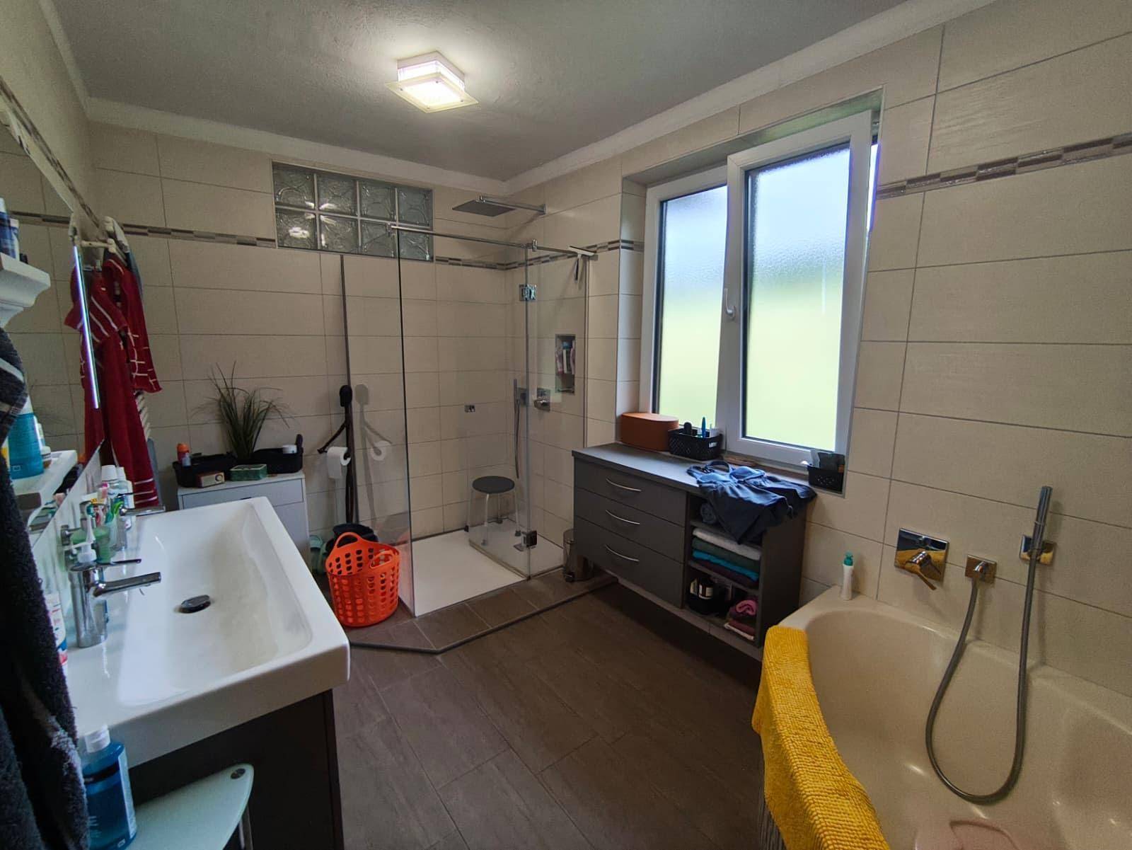 Geräumiges Badezimmer mit Badewanne, begehbarer Dusche, Einzelwaschbecken und Fenster.