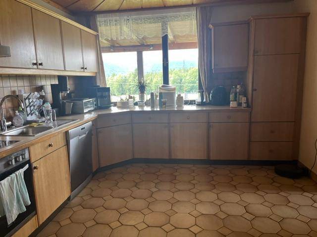 Geräumige Küche mit traditionellen Holzschränken, Fliesenboden und weitem Ausblick durch das Fenster.