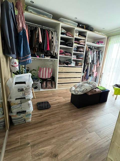 Begehbarer Kleiderschrank mit offenen Regalen und viel Stauraum, ausgestattet mit Holzboden.