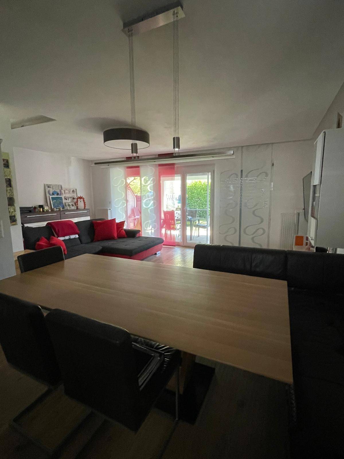 Geräumiger Wohn-Essbereich mit großem Holztisch, bequemer Sitzecke und Zugang zur Terrasse.