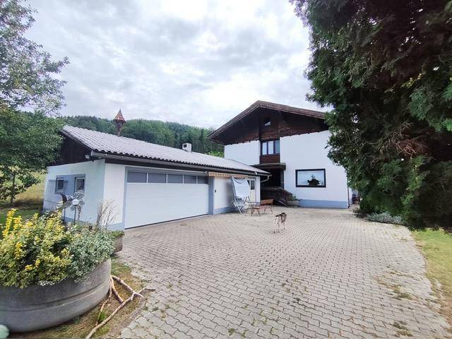 Einfamilienhaus mit angrenzender Garage und gepflasterter Zufahrt in ländlicher Umgebung.