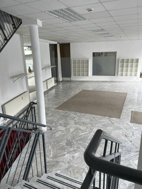 Offener Ladenbereich mit Marmorboden, Teppichakzenten und einer gut sichtbaren Treppe zum Obergeschoss.