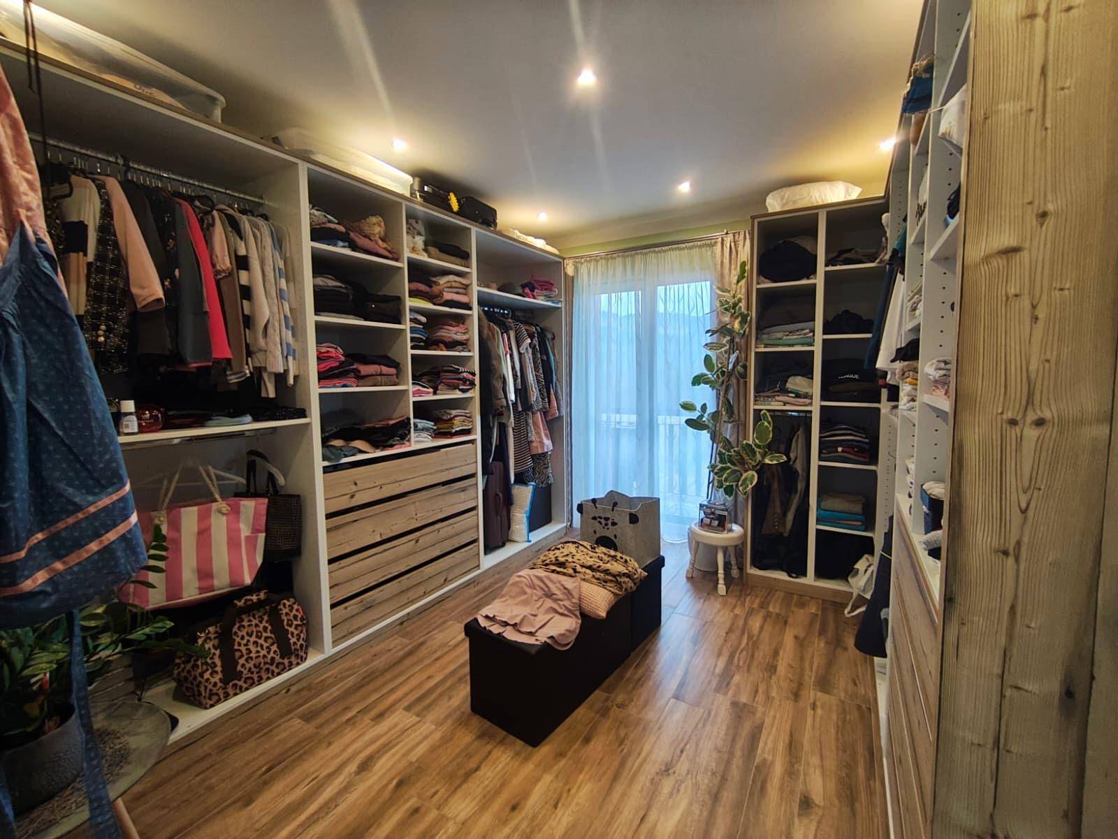 Großer begehbarer Kleiderschrank mit umfangreichen Aufbewahrungslösungen und Tageslicht.