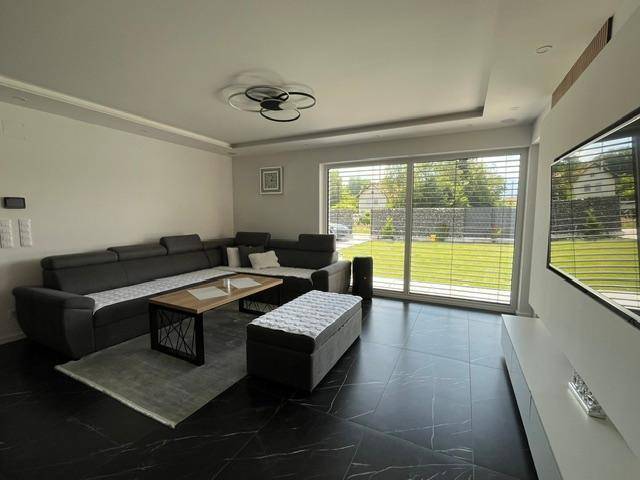 Helles Wohnzimmer mit großem Ecksofa, modernem Couchtisch und Zugang zum Garten.
