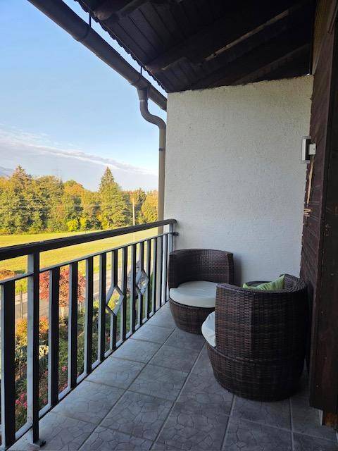Kleiner Balkon mit Korbsesseln und weitem Blick auf die grüne Landschaft und Berge.