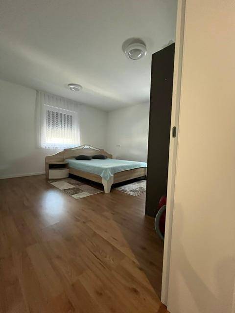 Helles Schlafzimmer mit Holzboden, modernem Bett und schlichten Nachttischen.