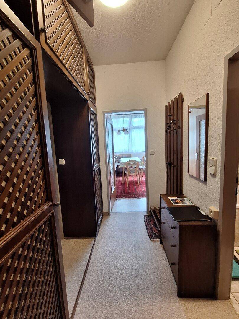 Heller Flur mit Einbauschränken, Teppichboden und Blick in den Essbereich.