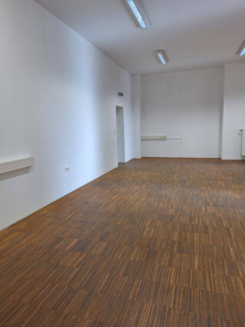 Großer, leerer Büroraum mit Holzboden und weißen Wänden, bereit zur Einrichtung.