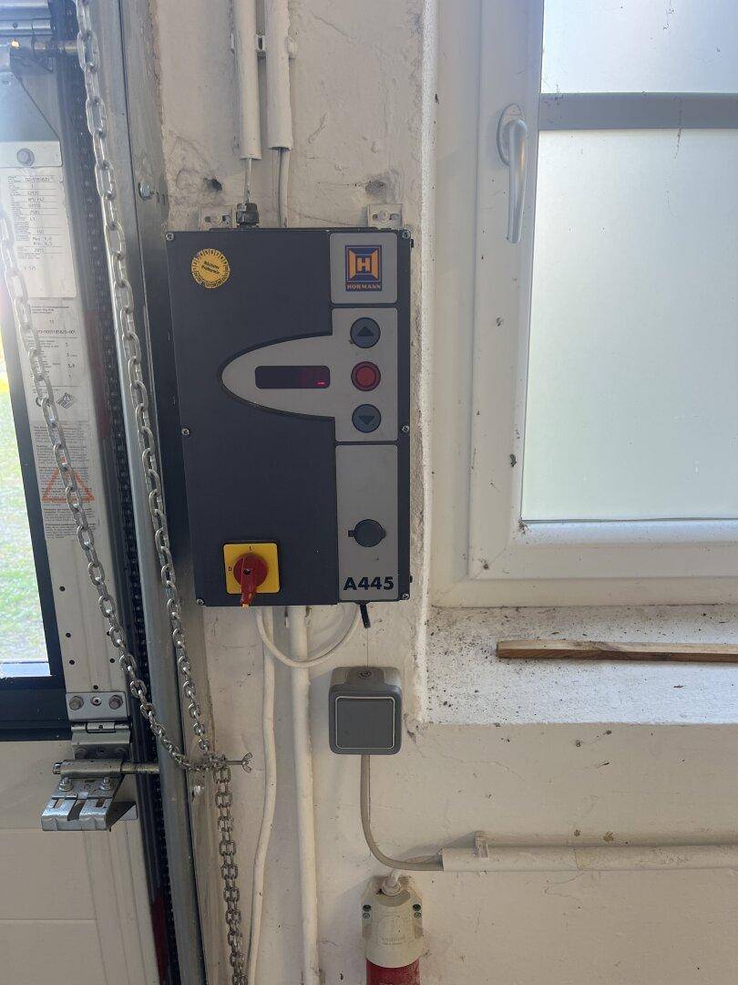 Nahaufnahme eines Steuerkastens für ein Garagentor, an der Wand neben einem Fenster montiert.
