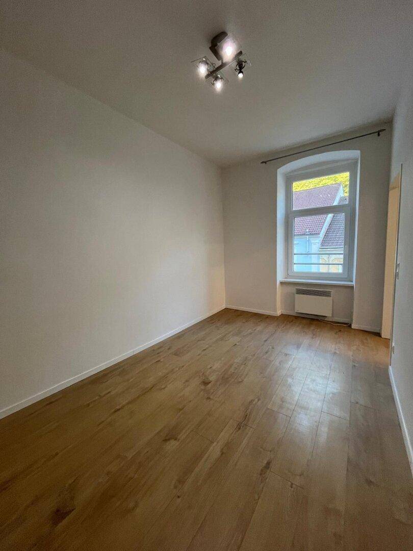 Geräumiger, heller Raum mit Holzfußboden und einem Fenster, ideal für verschiedene Nutzungen.