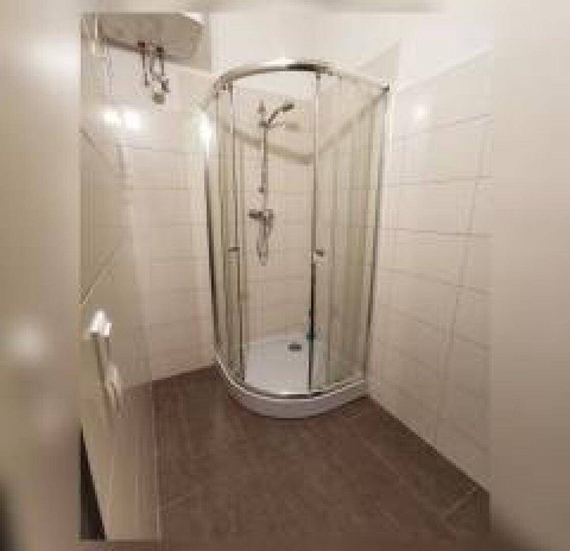 Badezimmer mit einer runden Duschkabine und hellen Fliesen.