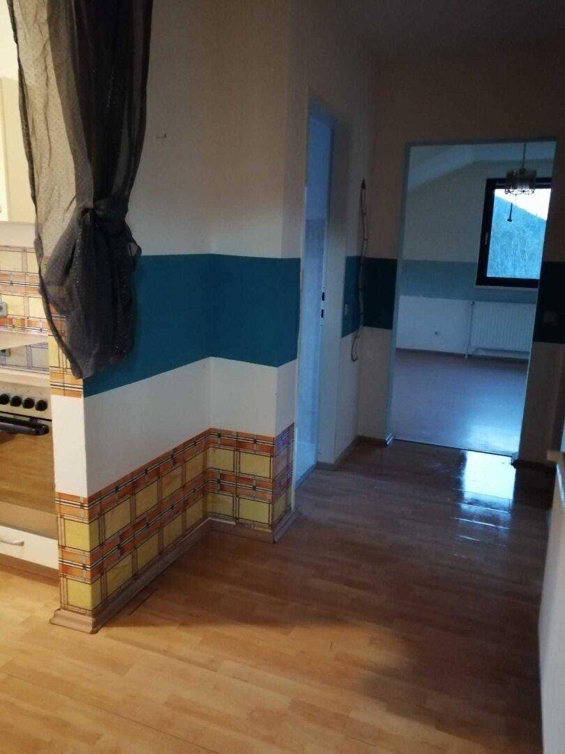 Flur mit Laminatboden und farbigen Wänden, der zu weiteren Räumen führt.