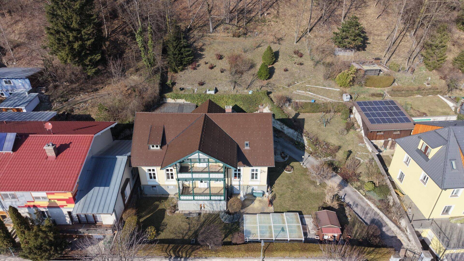 Luftaufnahme des historischen Hauses mit Garten und umliegender ländlicher Bebauung.