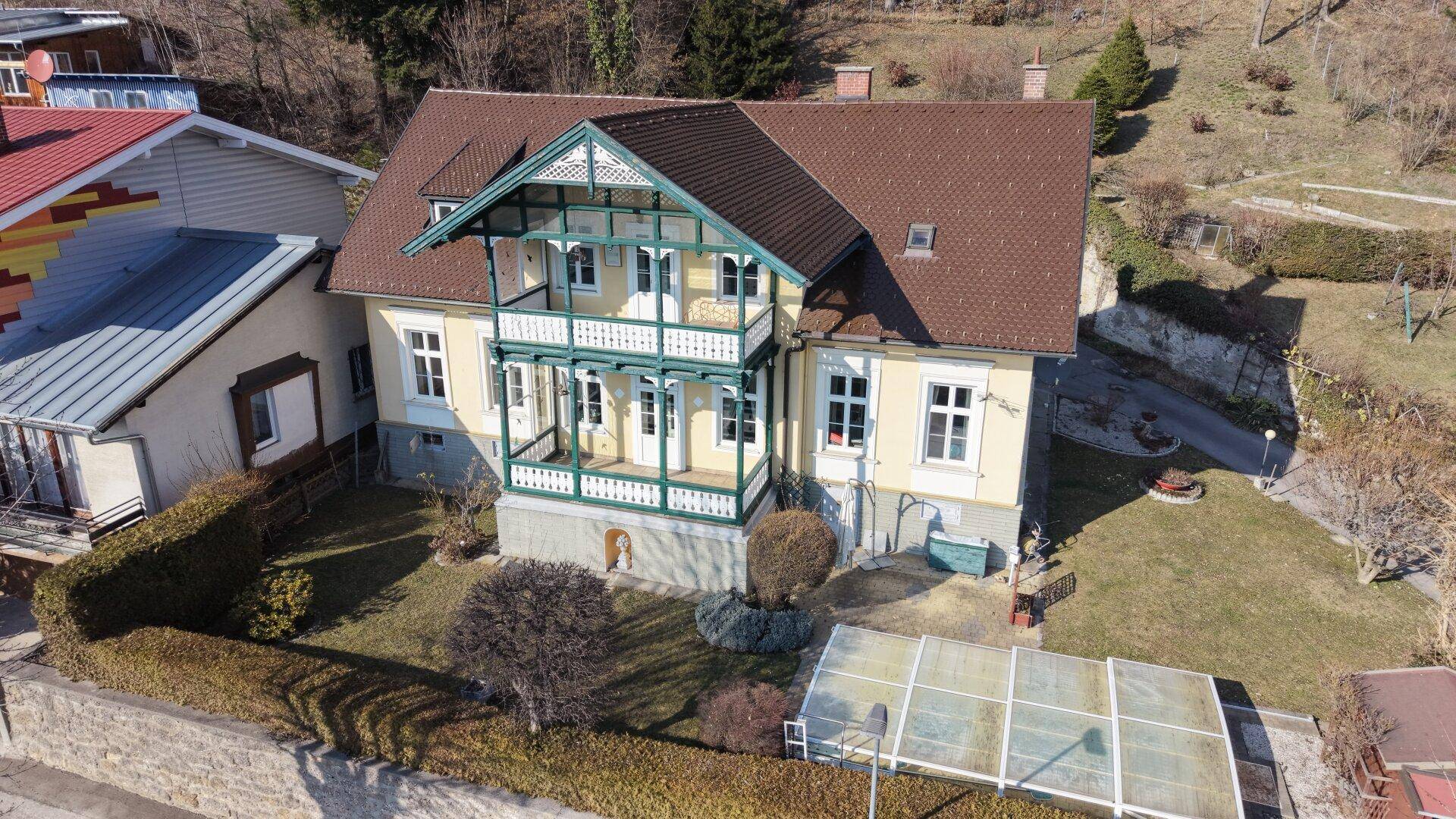 Frontansicht des historischen Hauses mit dekorativen Balkonen und gepflegtem Vorgarten.