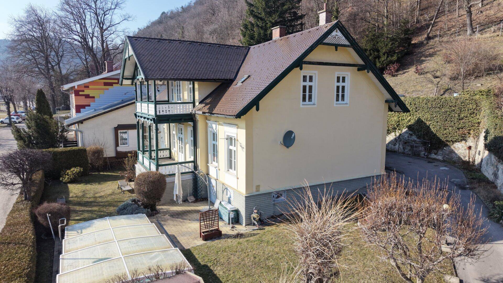 Seitenansicht des historischen Hauses mit Garten, Zufahrt und angrenzender Hecke.