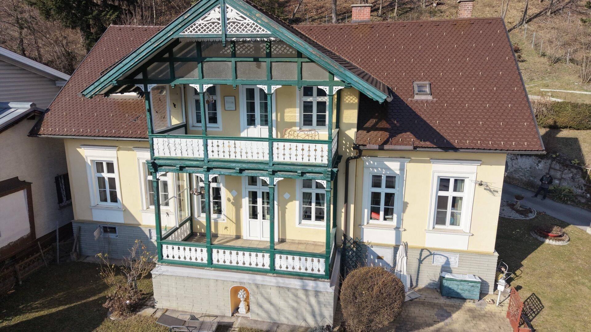 Frontansicht des historischen Hauses mit aufwendig gestalteten Balkonen und Gartenbereich.