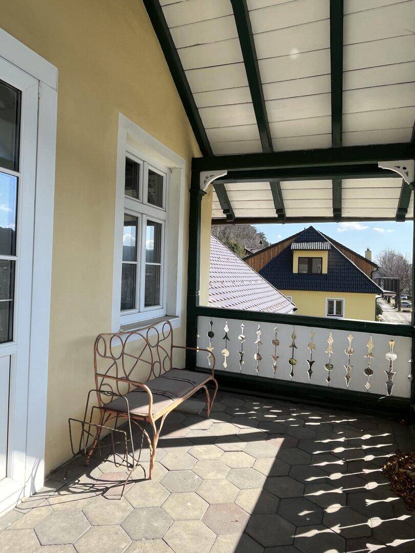 Überdachter Balkon mit Fliesenboden und traditionellem Geländer, ideal zum Entspannen.