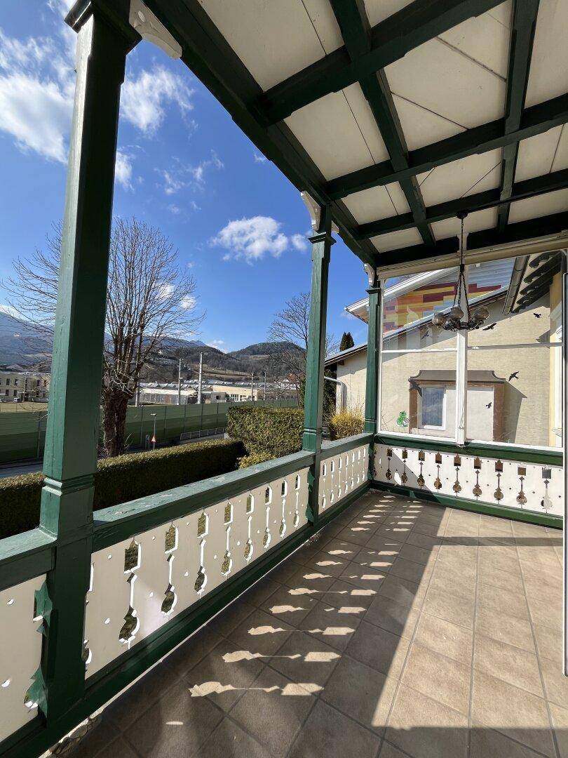 Überdachter Balkon mit Fliesenboden und Blick auf die Umgebung.