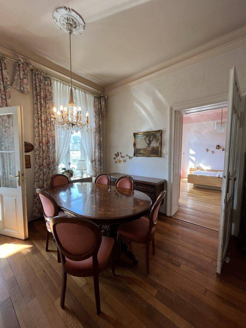 Elegantes Esszimmer mit Holzboden, Kronleuchter und Zugang zum Schlafzimmer.