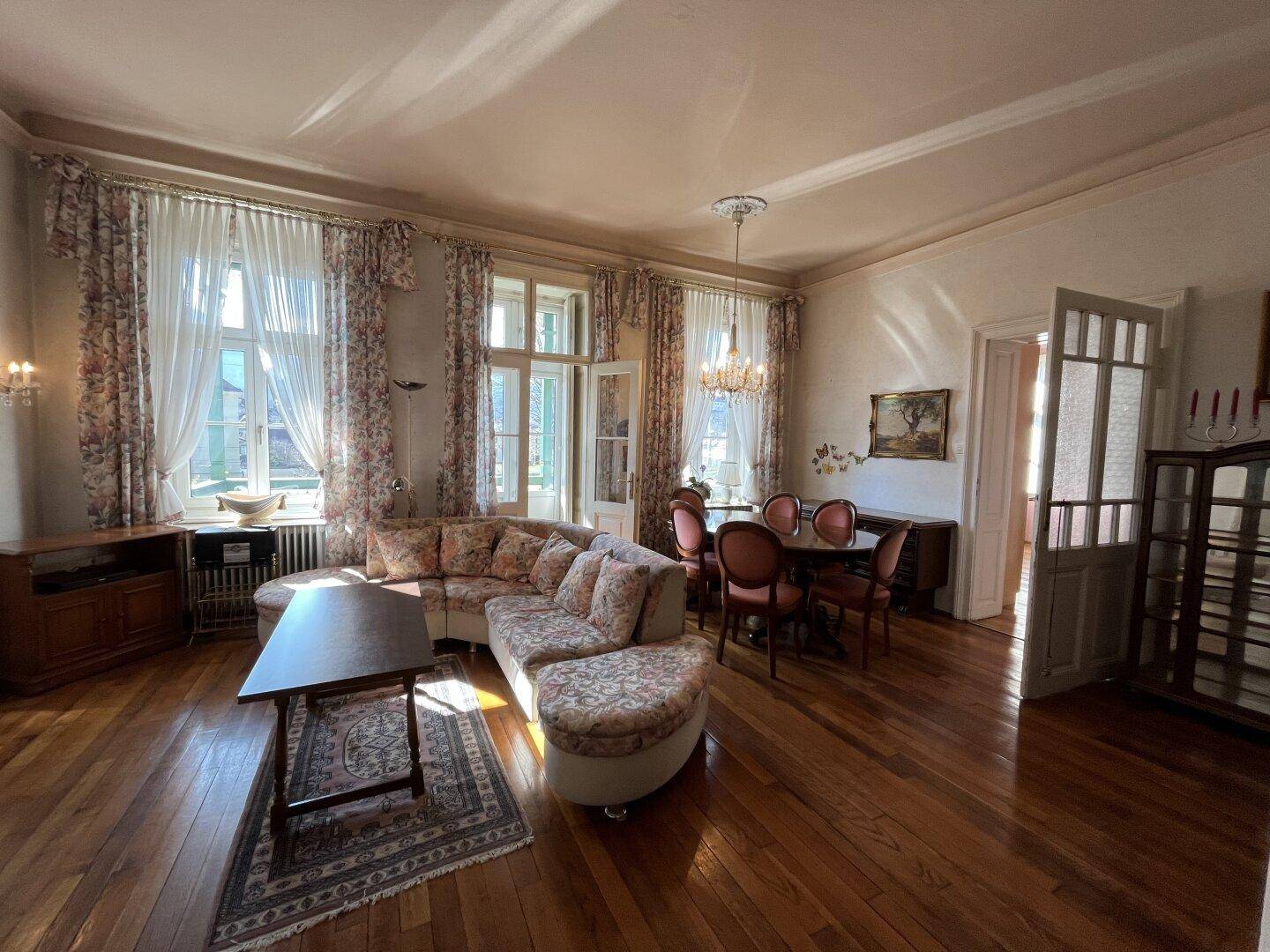 Heller Wohn-Essbereich mit Holzboden, großem Sofa und elegantem Esstisch.